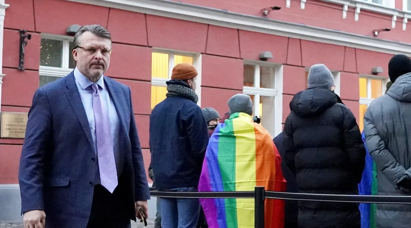Dziedošā protesta dalībnieki ar varavīksnes karogu pie Saeimas
